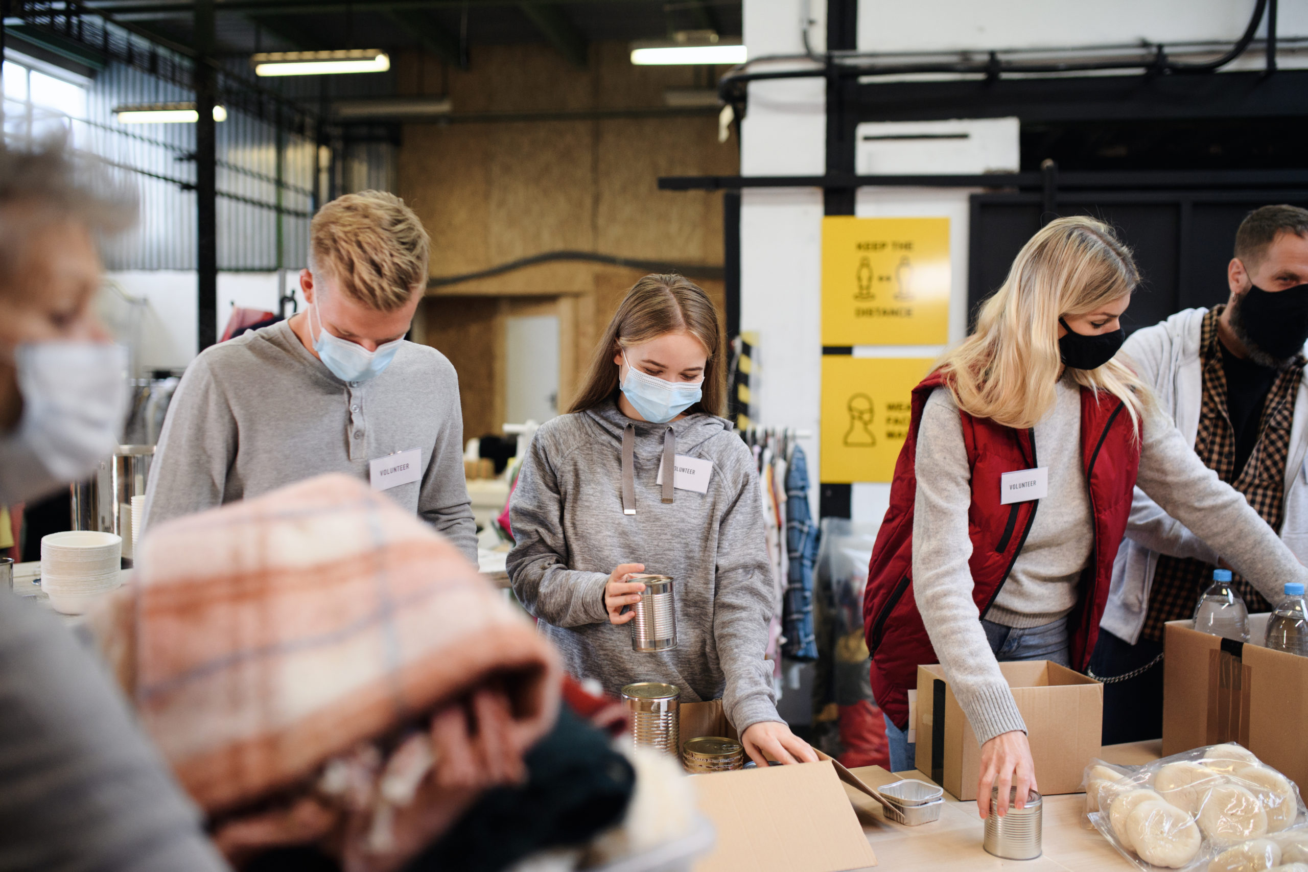 Group of volunteers in community charity donation center, food bank and coronavirus concept.