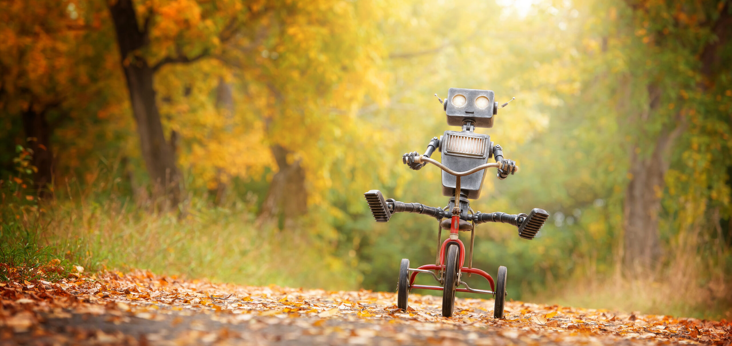 Happy humanoid robot rides a bicycle along the autumn alley. Robotic object experiences feelings and emotions. Concept of technology development in the form of artificial intelligence.