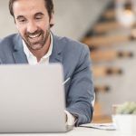 Man smiling, looking at computer
